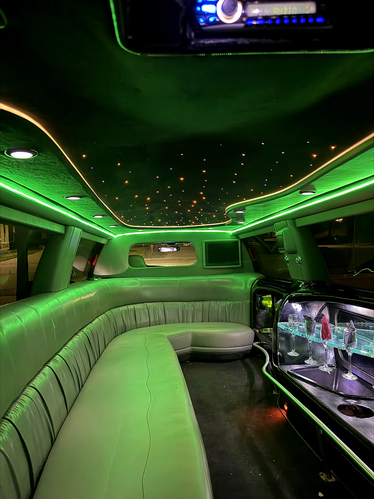 The bar in the stretch limousine, glassware set out under the lit shelf
