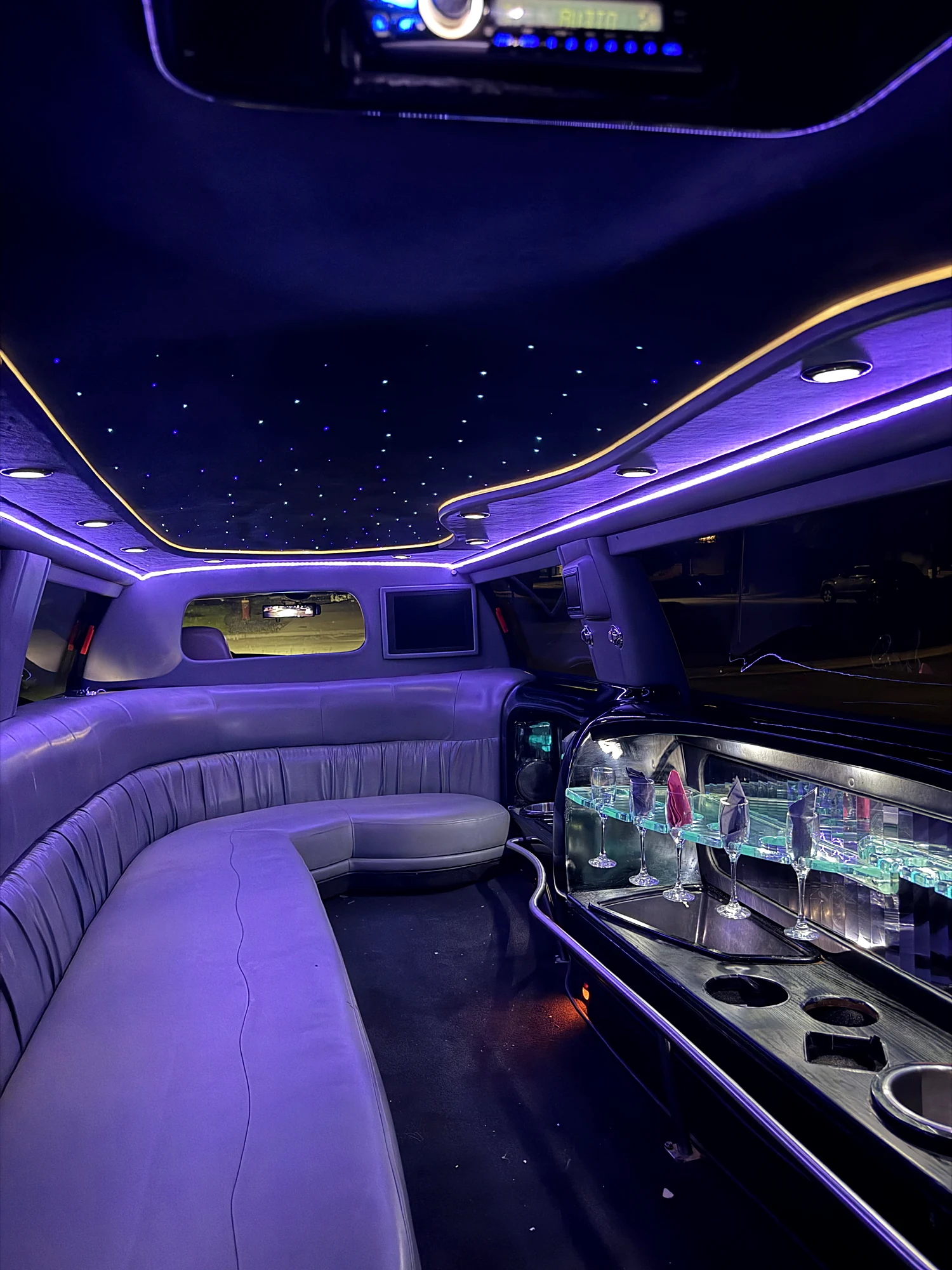 Cabin of the Ford Excursion stretch limousine lit in purple, with the bar and fibre-optic roof